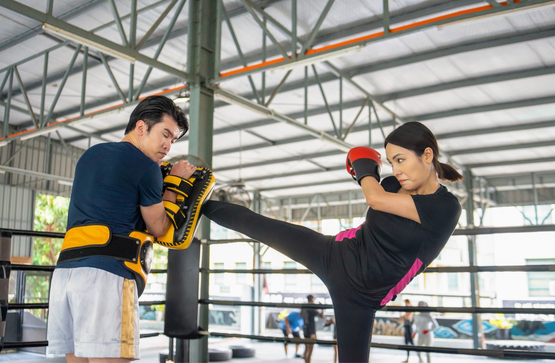 Kickboxerin übt mit Trainer im Boxring