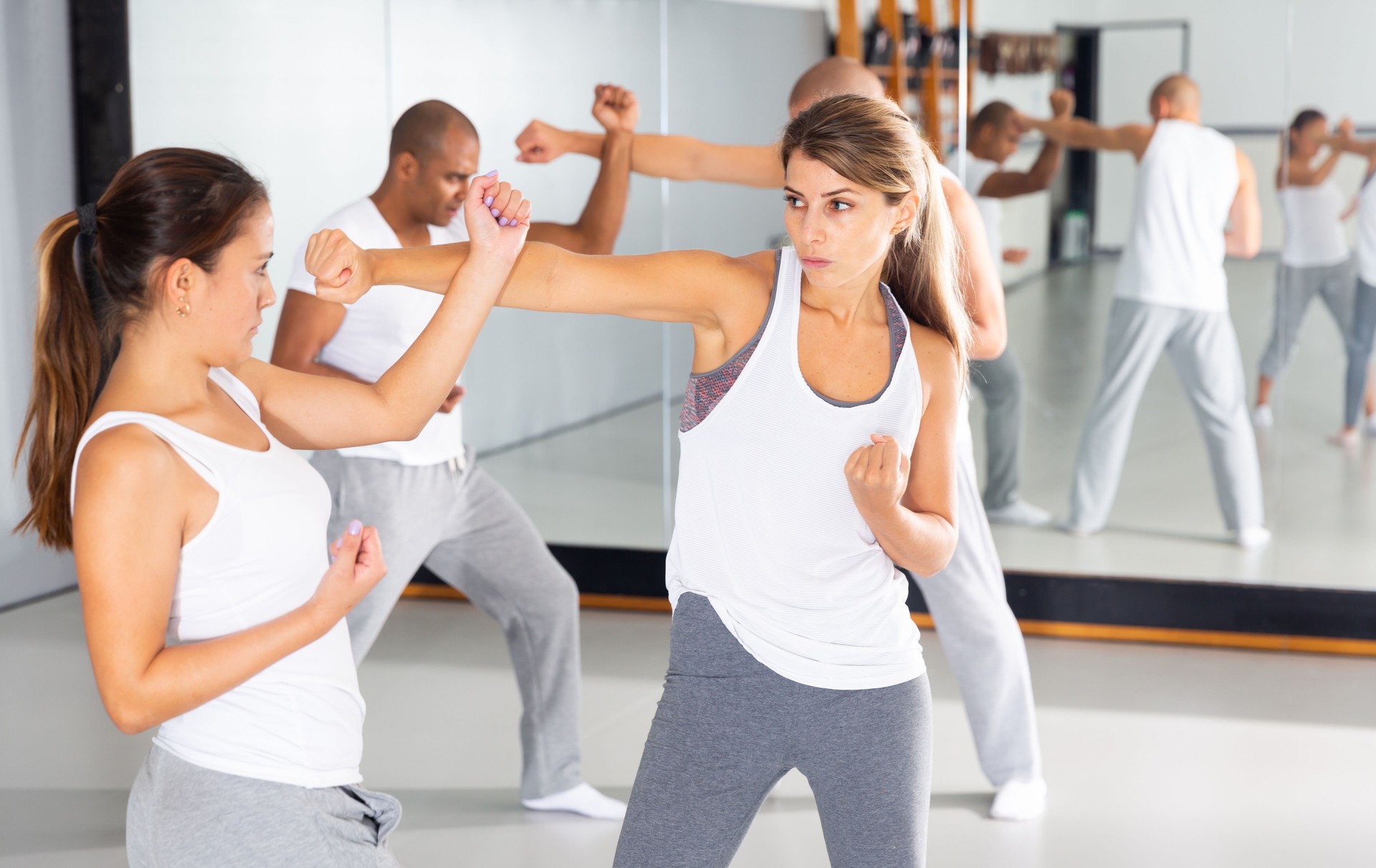 Zwei junge Frauen üben grundlegende Selbstverteidigungsfähigkeiten im Fitnessstudio
